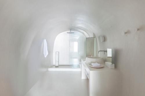a white bathroom with a sink and a mirror at Aesthesis Boutique Villas Firostefani in Firostefani