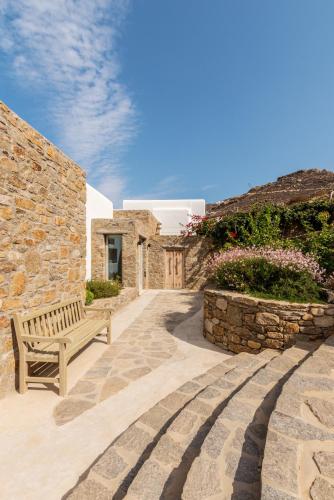 a wooden bench sitting in front of a stone building at Villa Amra - Secluded Mykonos Haven with Sea Views, Heated Pool, Gym & Hammam in Elia