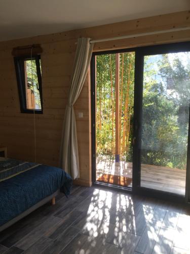 een slaapkamer met een bed en een grote glazen schuifdeur bij Un temps pour le rêve in Valence