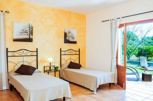 a bedroom with two beds and a door to a yard at Casa Calonge in Felanitx