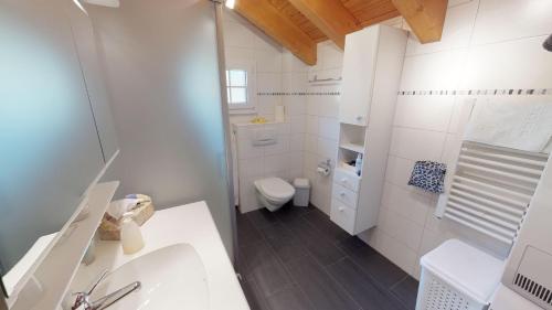 a white bathroom with a toilet and a sink at Andara in Belalp