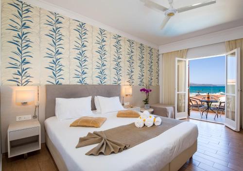a bedroom with a large bed with a view of the ocean at Kalyves Beach Hotel in Kalyves