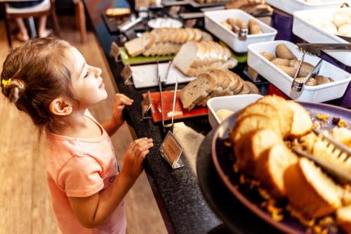 a little girl looking at a buffet of food at Novotel Porto Alegre Airport in Porto Alegre