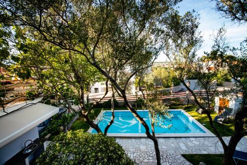een uitzicht over een zwembad in een tuin met bomen bij Villa Neroli in Krk