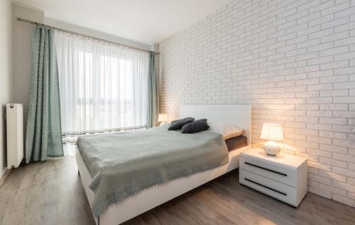 1 dormitorio con 1 cama y pared de ladrillo blanco en Galeria Rondo Wiatraczna Apartments, en Varsovia