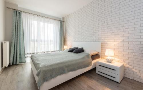 ワルシャワにあるGaleria Rondo Wiatraczna Apartmentsの白レンガの壁、ベッド付きのベッドルーム1室