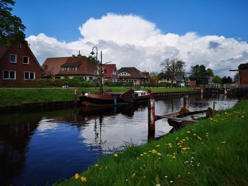 a couple of boats docked on a river with houses at Ferienhaus Moorspatz, 95143 in Rhauderfehn