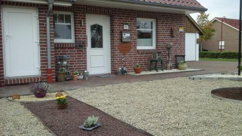 a brick house with a white door and a patio at Ferienhaus Moorspatz, 95143 in Rhauderfehn
