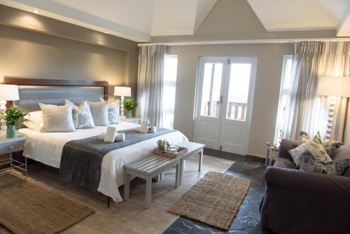 a bedroom with a large bed and a living room at Whalesong Hotel & Spa in Plettenberg Bay