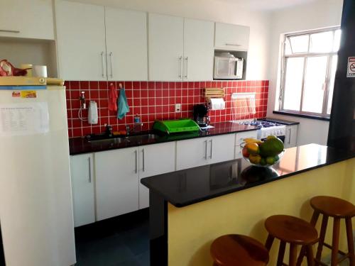 a kitchen with white cabinets and a counter with stools at Casa Babilonia in Rio de Janeiro