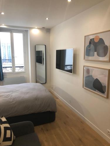 une chambre avec un lit et une télévision à écran plat dans l'établissement Studio design proche Champs-Elysées, à Paris