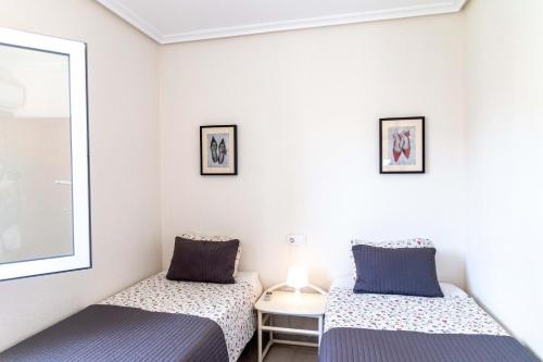 1 dormitorio con 2 camas y espejo en Playa Flamenca Casa 88 en Playa Flamenca