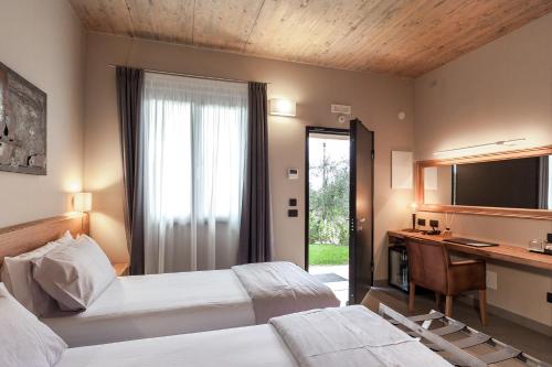 a bedroom with two beds and a desk and a television at Podere Vignanova Rooms & SPA in Castagneto Carducci
