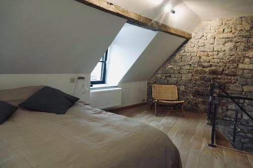 een slaapkamer met een bed en een stenen muur bij Le Grand George - Résidence Le Cercle in Marche-en-Famenne