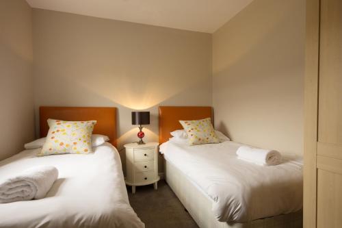 a bedroom with two beds and a table with a lamp at Kedleston Cottage - Darwin Lake Holiday Village in Matlock