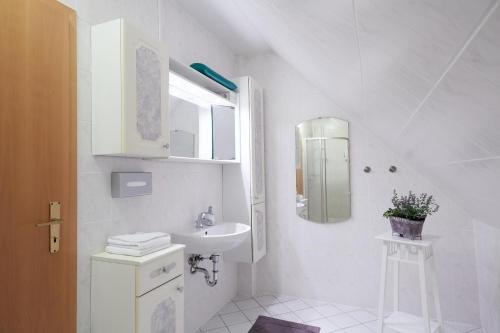 a white bathroom with a sink and a mirror at Hotel garni "Zum Eichwerder" in Templin