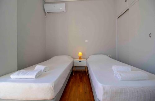 two beds in a room with a lamp on a night stand at Laconian Collection #Othonos luxury apartment# in Sparti