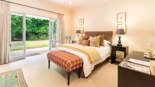 a bedroom with a bed and a desk and a window at Arum Hill Lodge in Balgowan