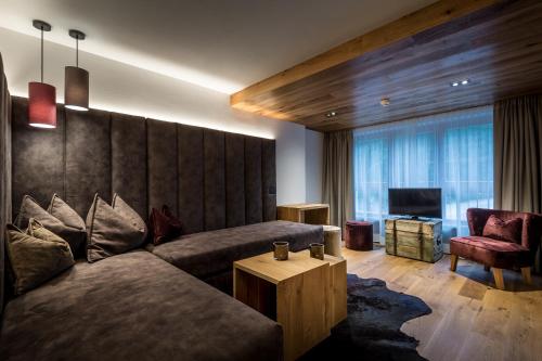 a living room with a couch and a tv at Hotel Des Alpes in La Villa