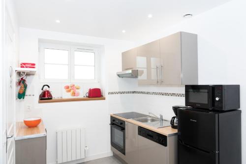 - une cuisine blanche avec un réfrigérateur noir et un évier dans l'établissement in the dream of Disneyland Paris, à Serris