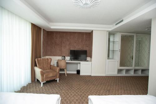 a hotel room with a television and a chair at Boyuk Ashirim Hotel in Ganja