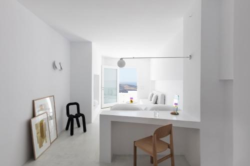 a white bedroom with a bed and a desk at Aesthesis Boutique Villas Fira in Fira