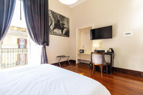 Schlafzimmer mit einem Bett, einem Schreibtisch und einem TV in der Unterkunft Gramsci Suites in Neapel