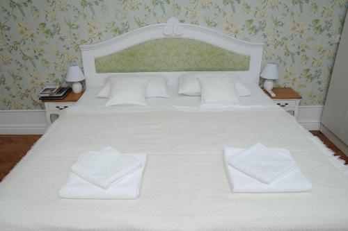 1 cama blanca grande con 2 toallas blancas. en Sophie Apartment, en Oradea