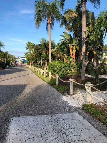 a street with palm trees and a rope fence at Captiva Beach Resort (open private beach access) in Sarasota