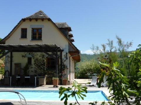 une maison avec une piscine devant une maison dans l'établissement Au Riverain, à Vieillevie