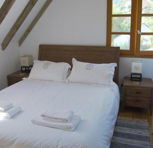 une chambre avec un lit blanc avec deux serviettes dessus dans l'établissement Au Riverain, à Vieillevie