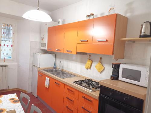 eine Küche mit orangefarbenen Schränken und einer Mikrowelle in der Unterkunft Appartamento Liliana in Pontremoli