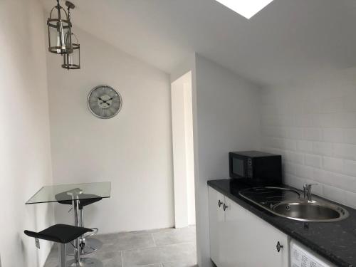 a kitchen with a sink and a clock on the wall at GROOMS COTTAGE OUTSIDE HOT TUB in Beith