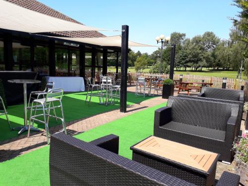 a patio with chairs and tables on green grass at Weald of Kent Golf Course and Hotel in Maidstone