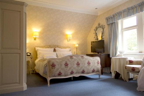a bedroom with a bed and a television in it at Corriegour Lodge Hotel in Letterfinlay
