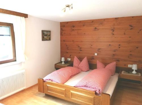 シュルンスにあるHaus Hubertusのベッドルーム1室(木製ヘッドボードとピンクの枕が備わるベッド1台付)