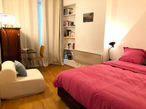 ein Schlafzimmer mit einem roten Bett und einem Stuhl in der Unterkunft L'appartement Magdebourg in Paris