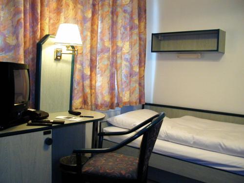 a room with a bed and a chair and a desk at Apart-Hotel-Pension in Taucha