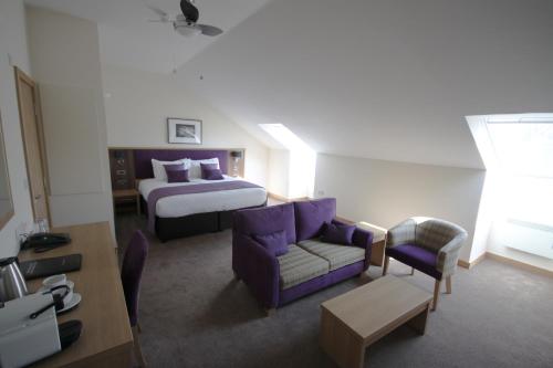 a hotel room with a bed and a couch at Weald of Kent Golf Course and Hotel in Maidstone