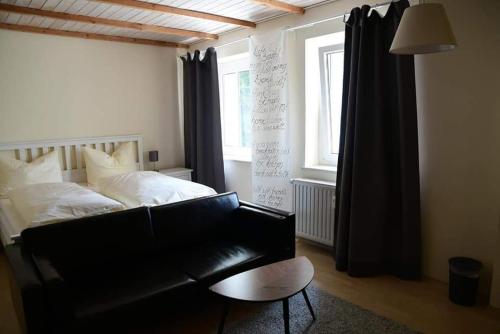 Hotel Berggasthof Waldlust في فونزيدل: غرفة نوم مع سرير وأريكة جلدية سوداء