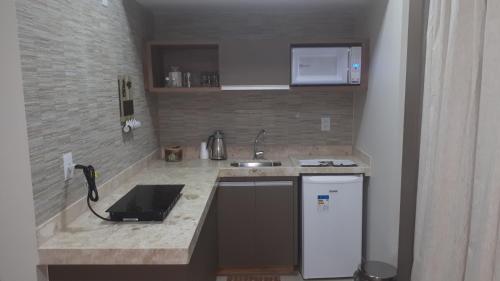 Una pequeña cocina con fregadero y estufa. en RIO QUENTE PARK VEREDAS Flat, en Rio Quente