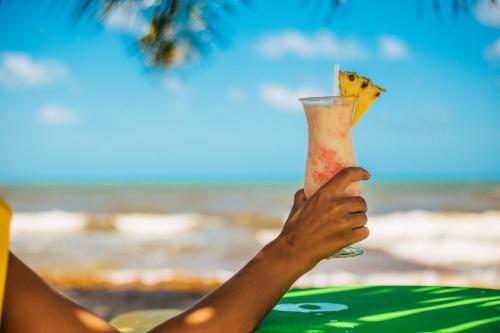 a person holding up a drink in front of the beach at Hopkins Bay Belize a Muy'Ono Resort in Hopkins