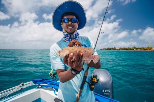 a man holding a fish in a boat at Hopkins Bay Belize a Muy'Ono Resort in Hopkins