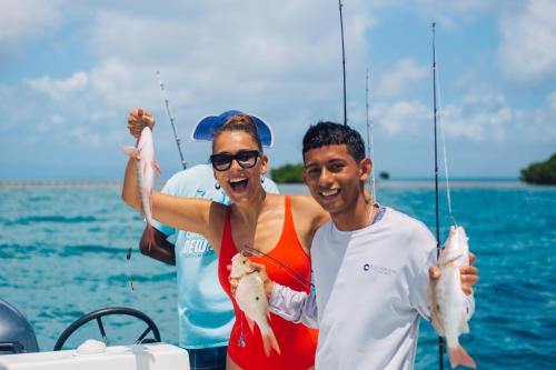 two people holding fish on a boat in the water at Hopkins Bay Belize a Muy'Ono Resort in Hopkins