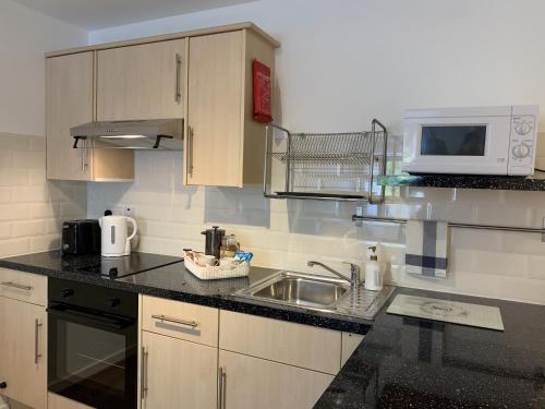a small kitchen with a sink and a microwave at Serviced Apartment Bristol One-Bedroom Southmead Hospital MOD Airbus in Bristol