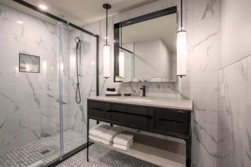 a bathroom with a sink and a shower with a mirror at Le Capitole Hotel in Quebec City