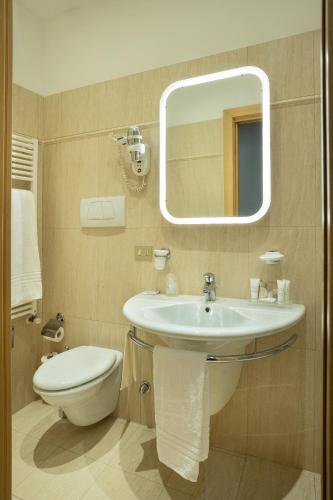 a bathroom with a sink and a toilet and a mirror at Best Western Plus Executive Hotel and Suites in Turin