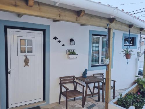 a porch with two chairs and a table and a door at Casa do Mar - Nazaré in Nazaré