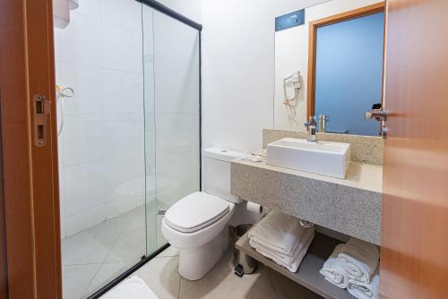 a bathroom with a toilet and a sink and a shower at Florida Mall & Suites in Limeira