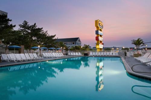 a pool with chairs and a hotel sign at dusk at Harrison Hall Hotel in Ocean City